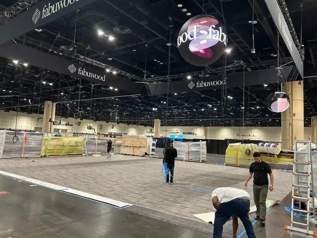 Early KBIS exhibit installation with flooring, overhead signage and staged booth materials