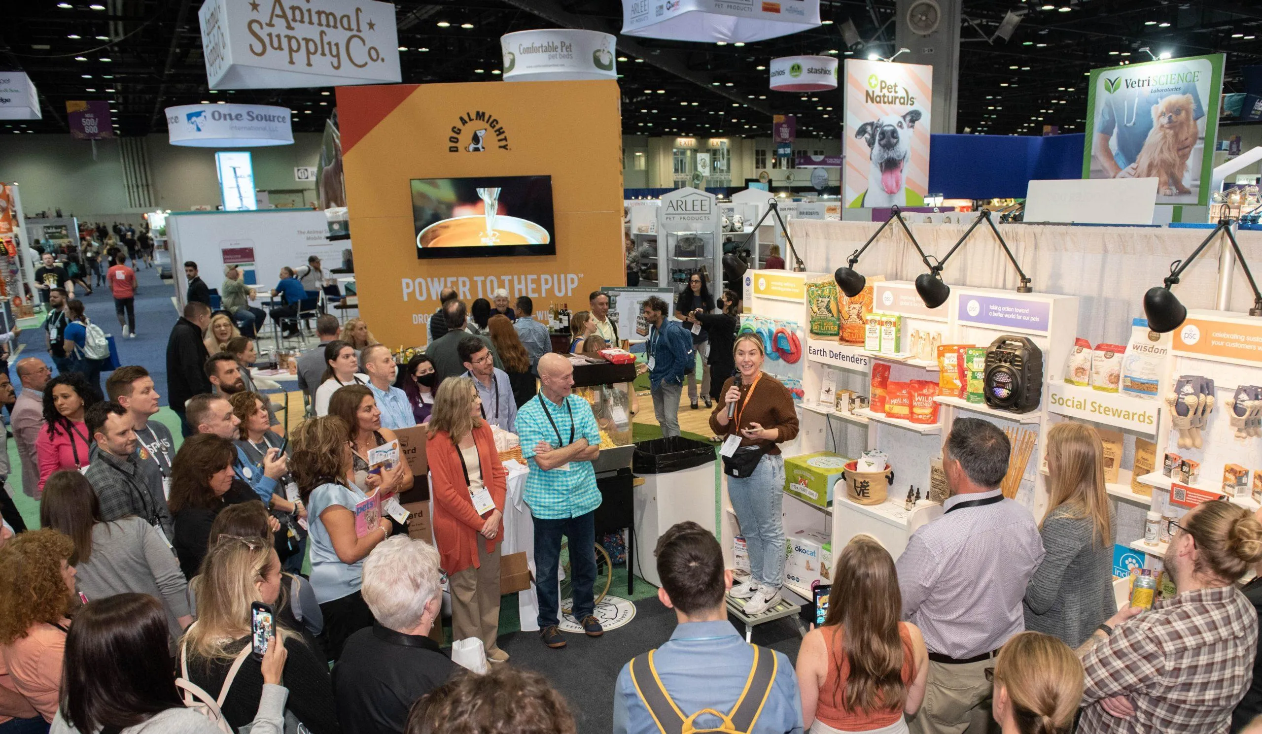Pet product demonstration and sampling station with booth staff engaging visitors at Global Pet Expo.