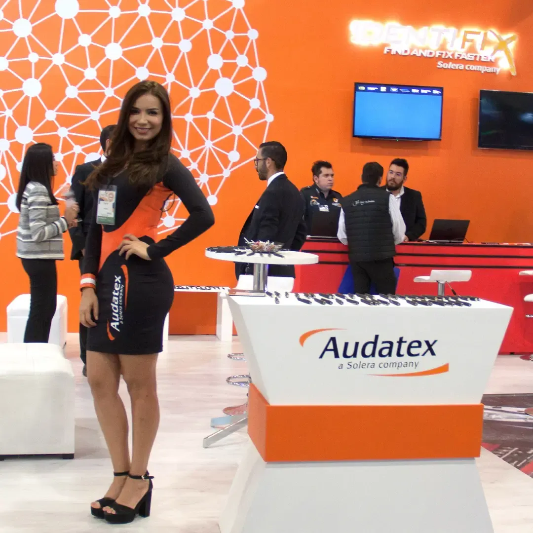 Attractive promotional model standing inside a branded corporate trade show booth