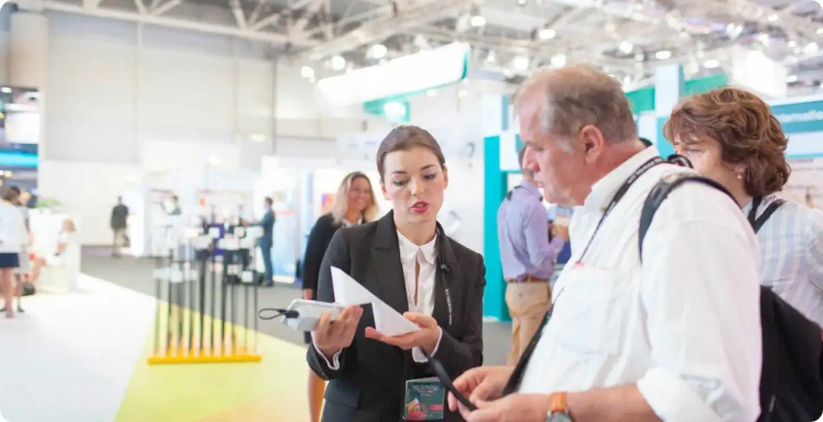 Trade show product specialist explaining a demonstration to exhibit visitors
