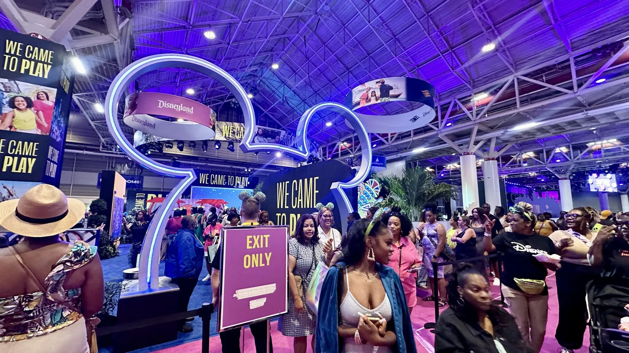Crowded Disney immersive exhibit booth with illuminated Mickey Mouse entrance at a New Orleans convention.