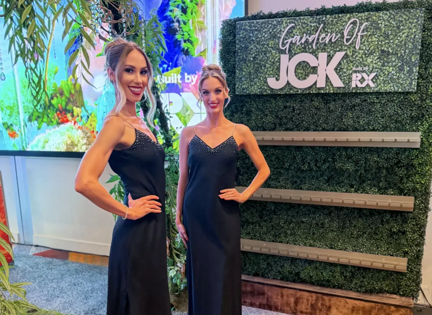 Two professional promotional models welcoming attendees at a colorful Las Vegas trade show exhibit booth