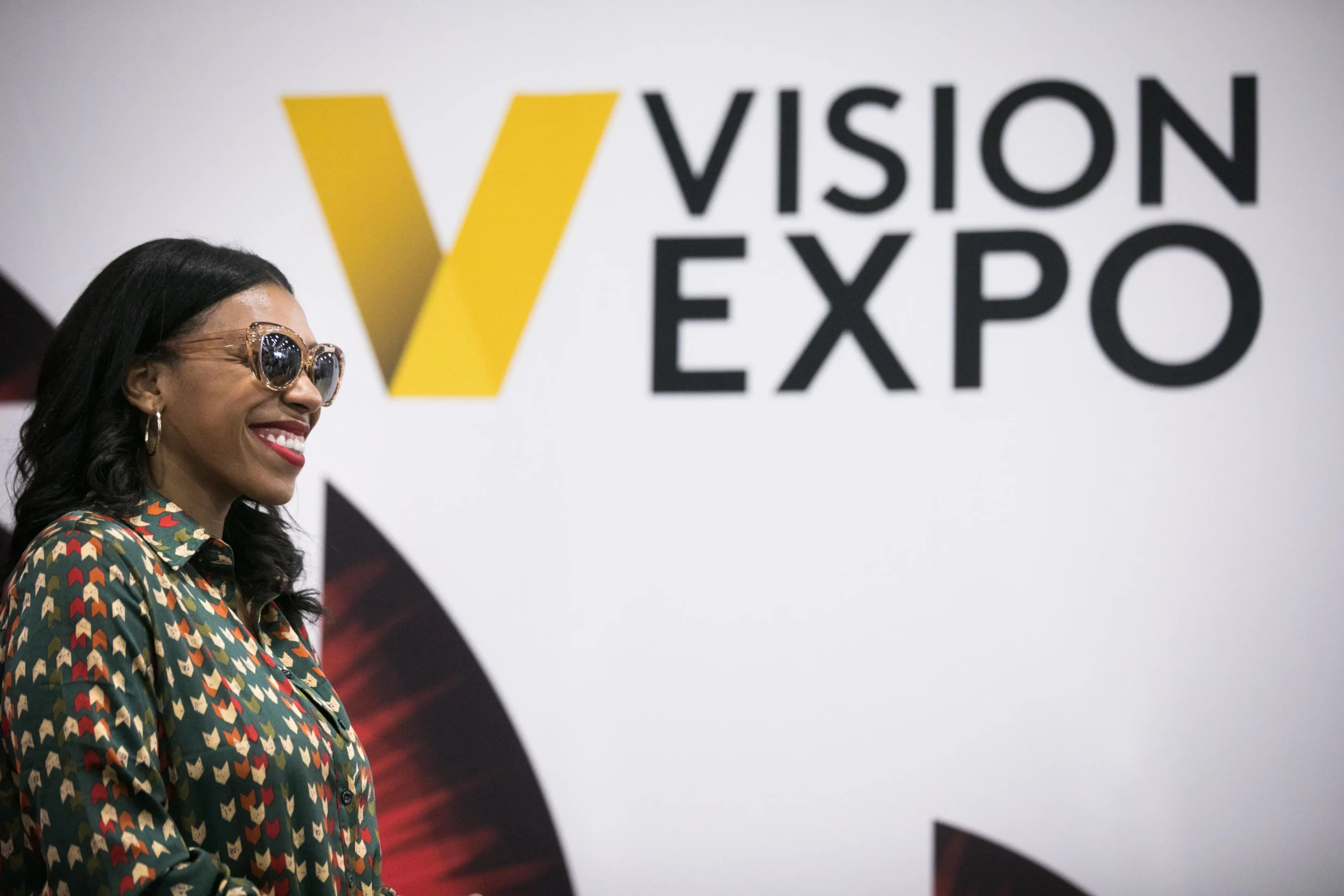 Female eyewear exhibitor showcasing optical brands on the Vision Expo Las Vegas trade show floor