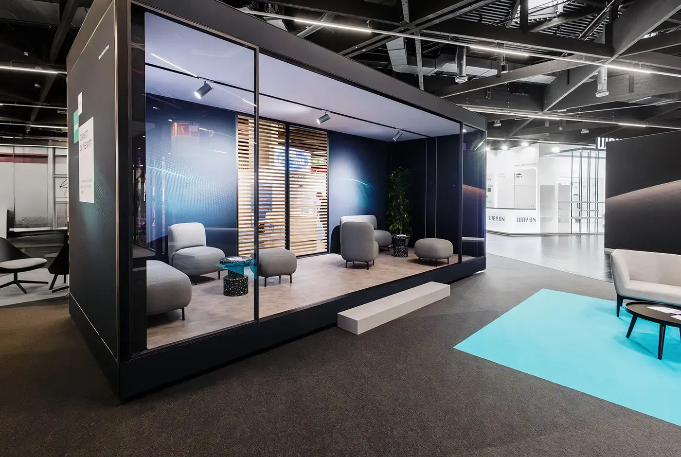 Modern trade show booth with branded displays, lounge seating and decorative lighting