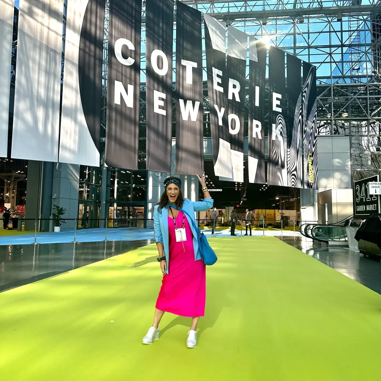 Attractive trade show attendee inside the Javits Center beneath the Coterie New York event logo