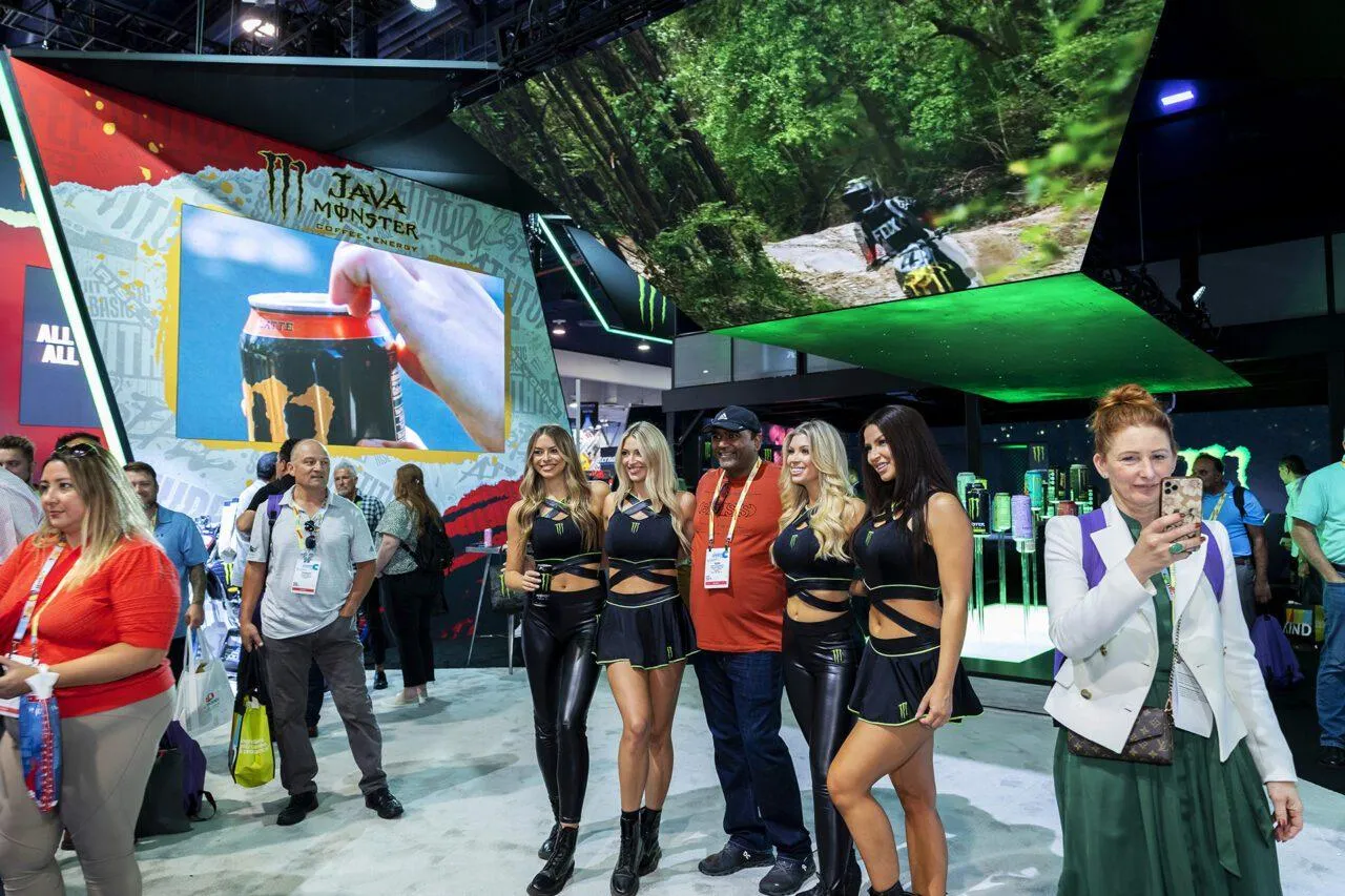 Monster Energy interactive trade show booth in Las Vegas with brand ambassadors, visitors and large LED video displays.