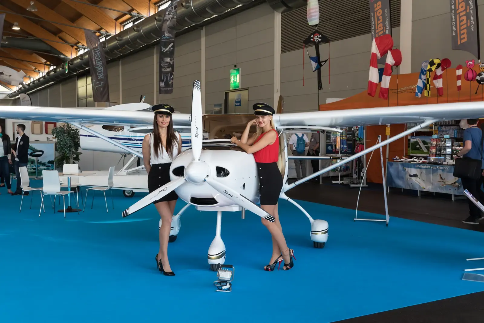 Two professional promotional models standing beside an aircraft display at a live trade show