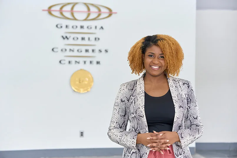 Professional woman standing inside the Georgia World Congress Center beside the venue’s official logo in Atlanta