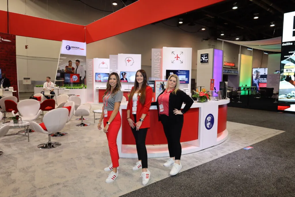 Three professional female aviation representatives inside a premium custom exhibit booth