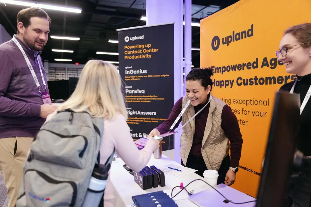 Trade show booth staff welcoming and engaging an attendee during a business exhibition.