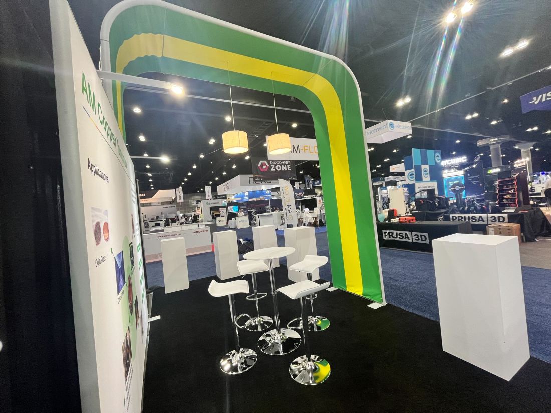 AM Copper 10x20 trade show booth with a green and yellow archway entrance and white product pedestals