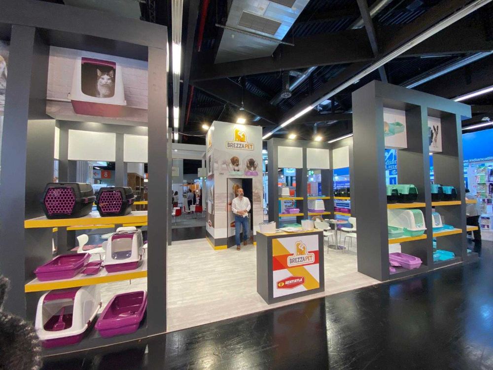 BrezzaPet 10x10 inline trade show booth with symmetrical white product shelving and lit header