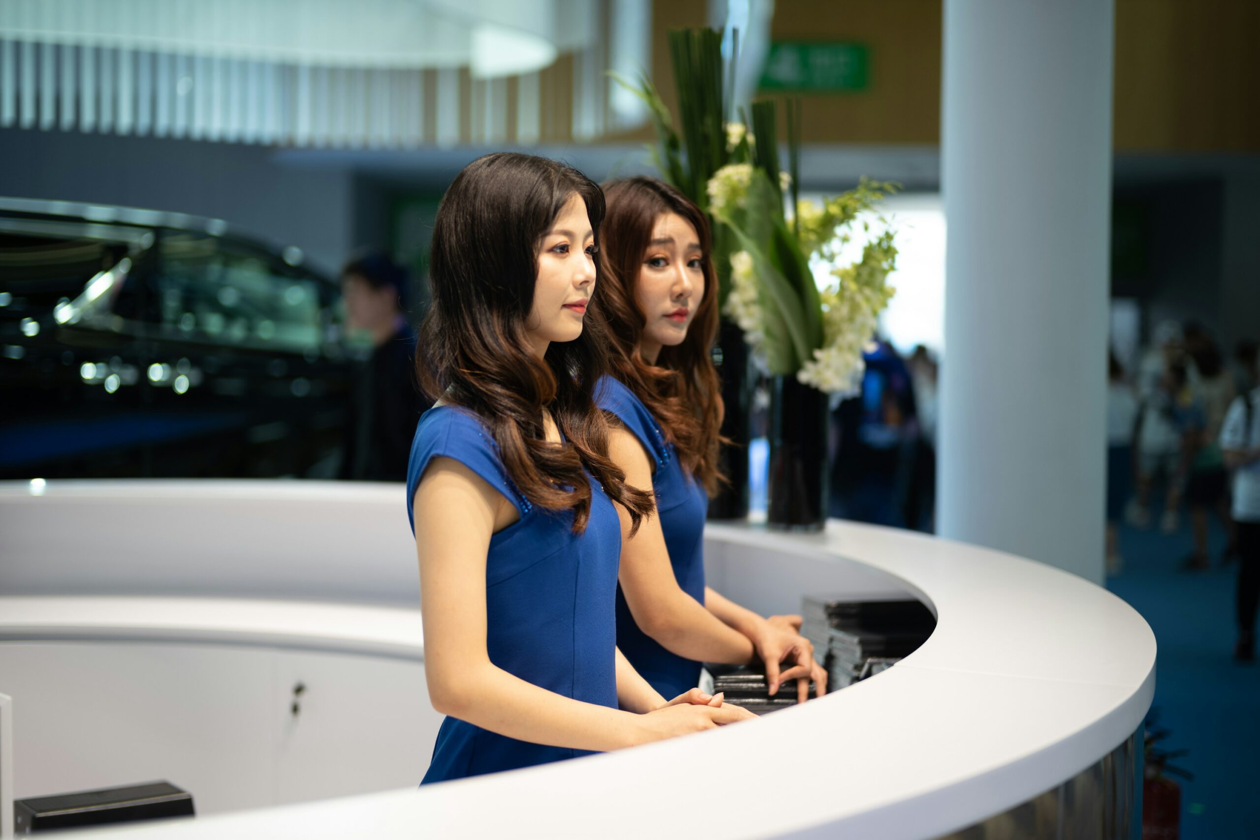 Two female event hosts welcoming visitors at an automotive exhibition