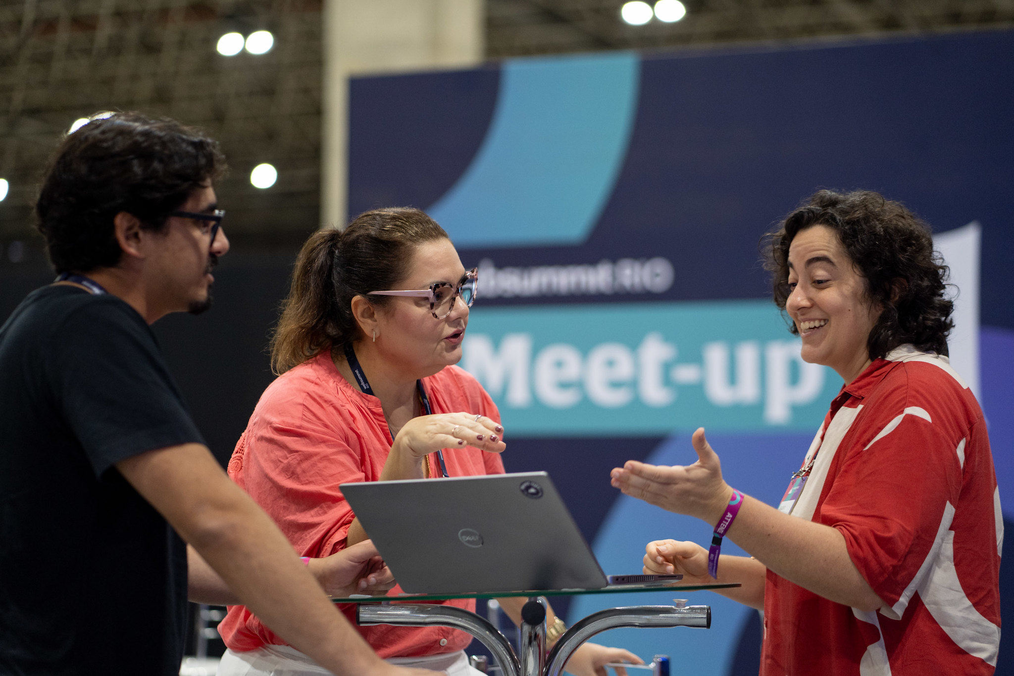 Two women and a man discussing information around a laptop on the exhibition floor