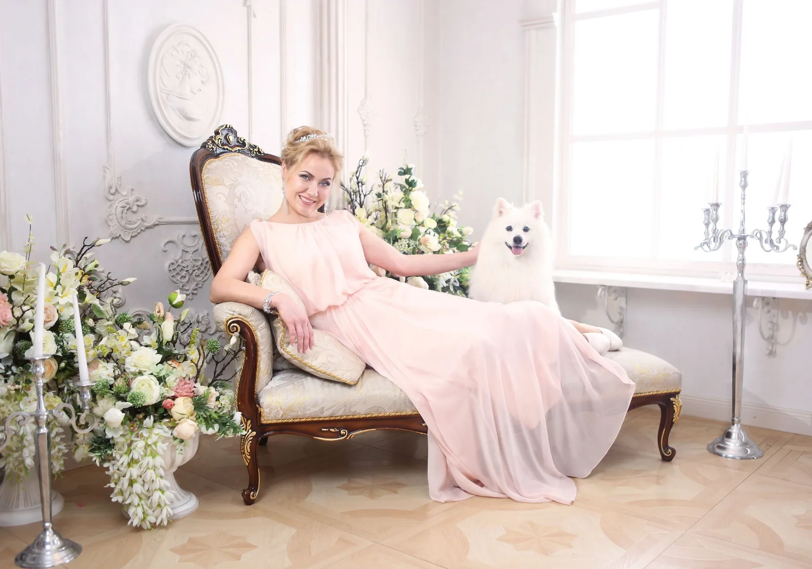 Glamorous woman in a pink gown reclining beside a white Samoyed dog
