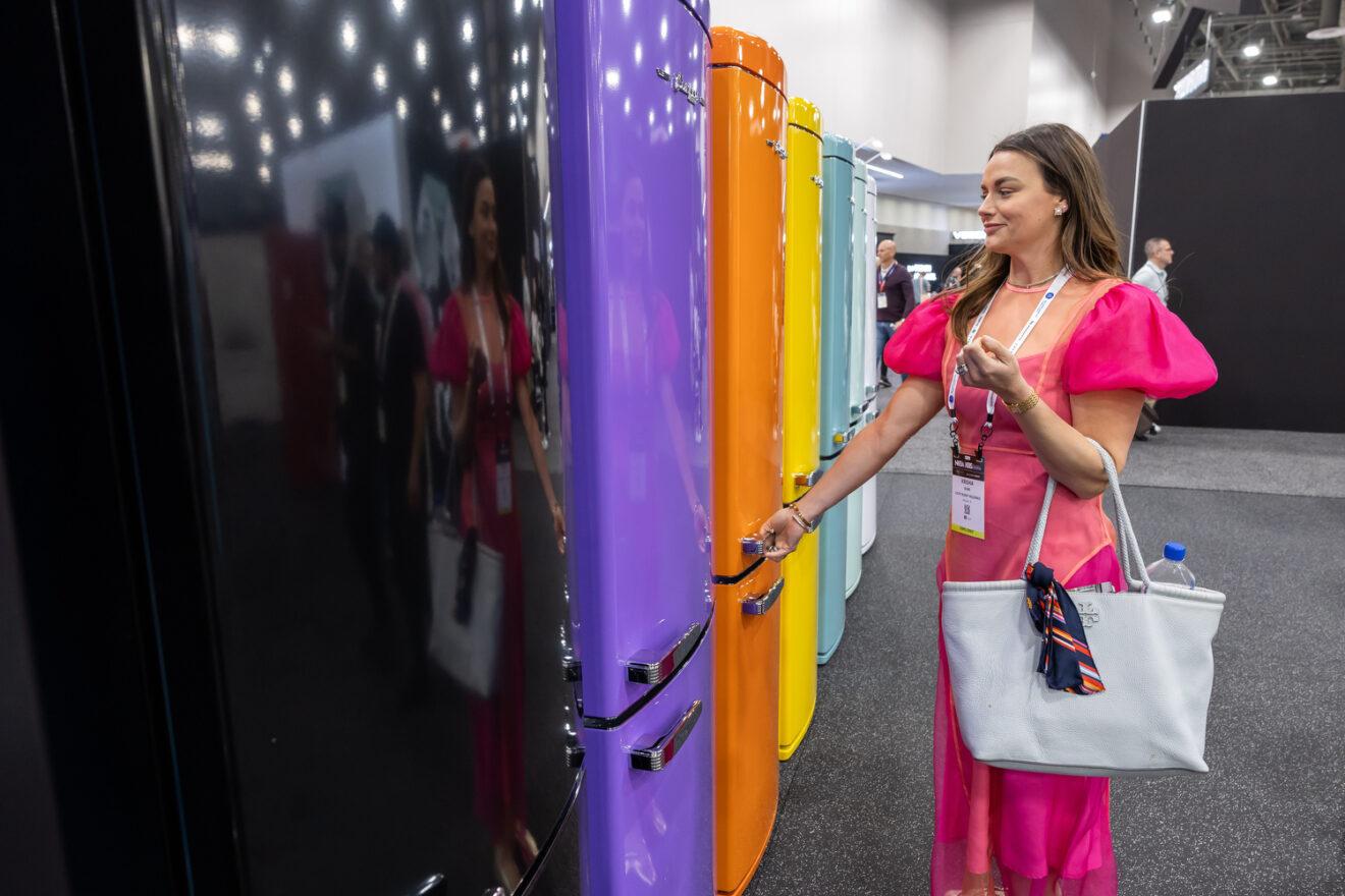 KBIS attendee opening one of a row of colorful retro refrigerators on the show floor