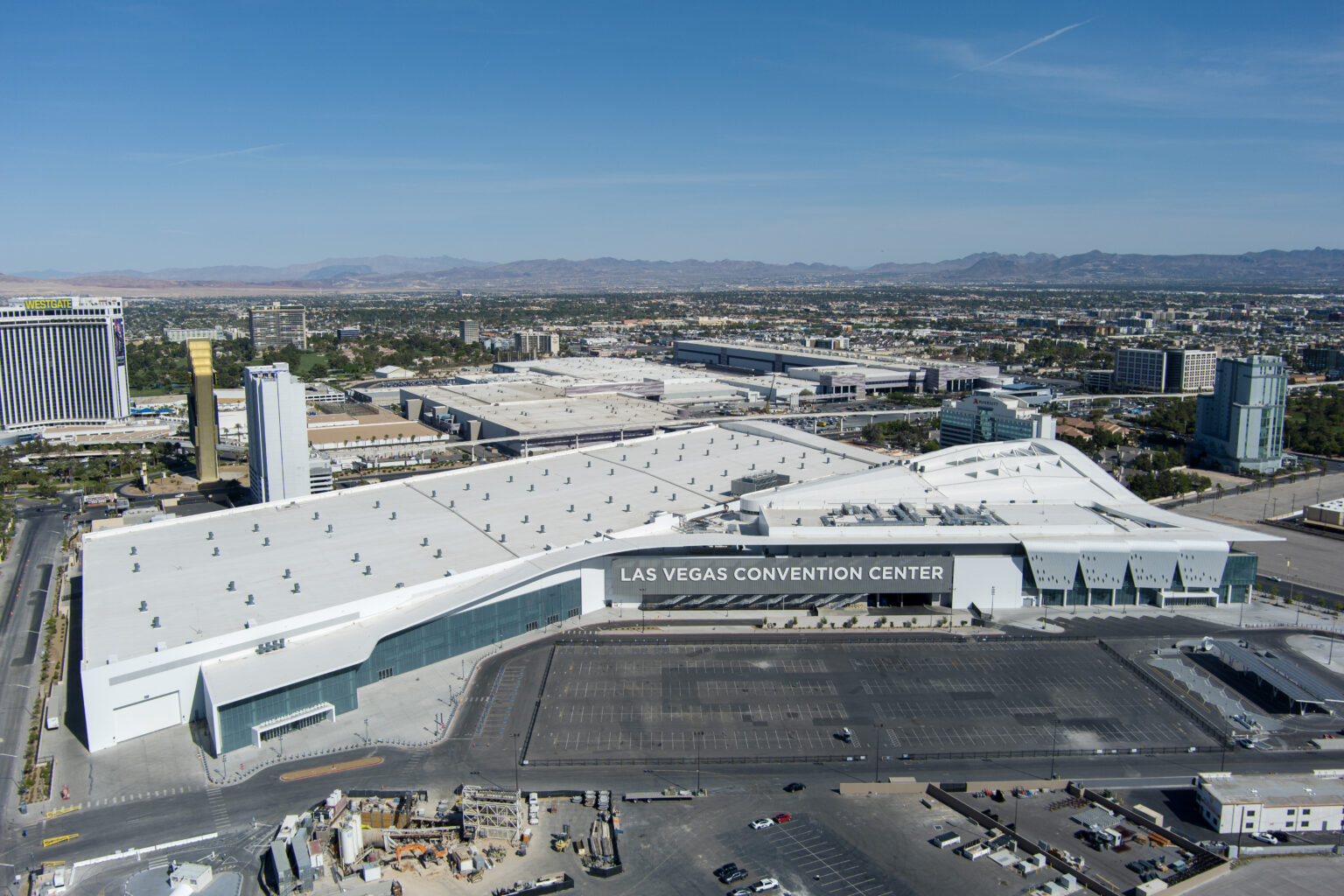 Aerial view of the Las Vegas Convention Center campus showing the connected exhibit halls, parking areas and the Las Vegas valley beyond