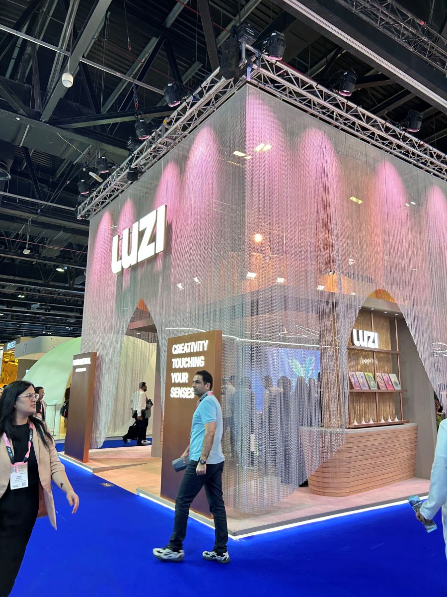Luzi 20x30 island trade show exhibit with chain curtain walls, pink truss lighting and arched entrances