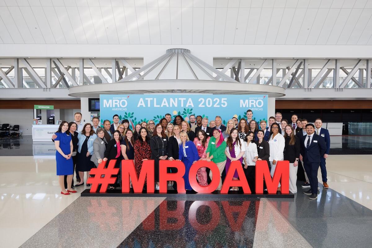 Dozens of aviation professionals gather for a group photograph in front of a large #MROAM sign at MRO Americas 2025 in Atlanta.