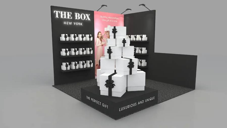Design rendering of a The Box New York 10x10 inline booth with a stacked gift-box centerpiece on a lit pedestal