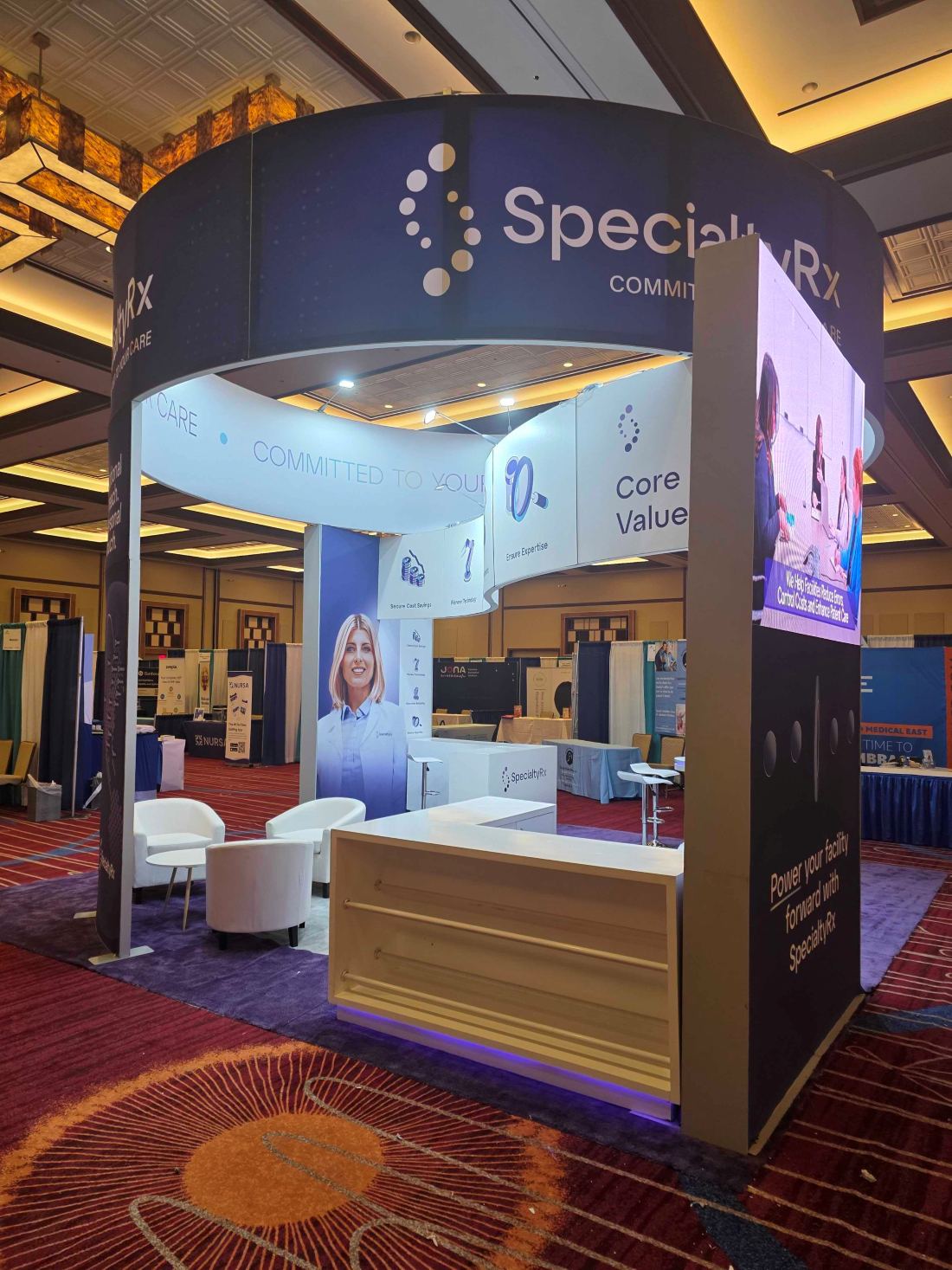 SpecialtyRx 20x20 island trade show booth lounge area with branded seating