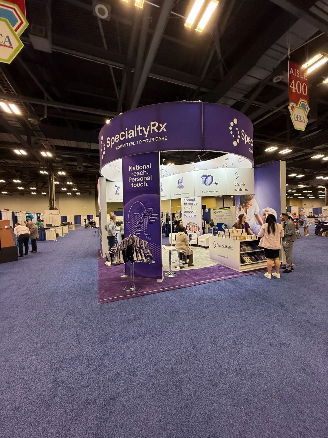 SpecialtyRx 20x20 island trade show booth with a circular fabric header and reception counter