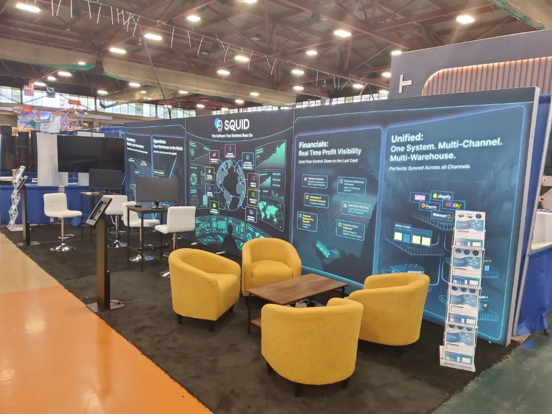 Squid 10x30 inline trade show exhibit with a full-length backlit graphic wall, lounge chairs and demo monitors