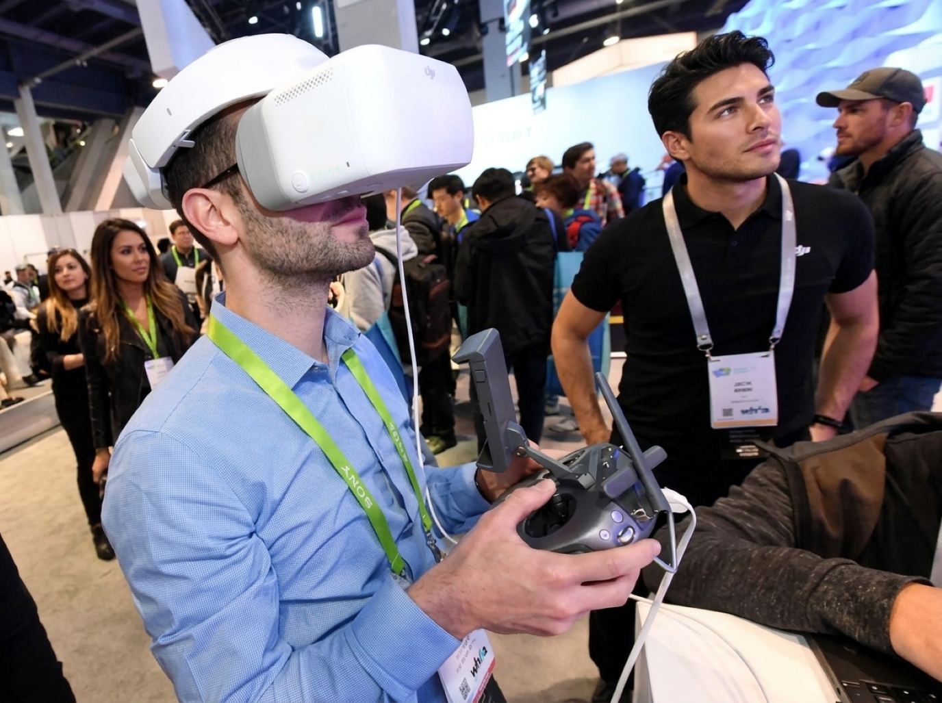 Booth staffer in a black polo guiding a visitor through a VR headset and drone demo, the hands-on booth staff Purple sends to San Jose tech shows