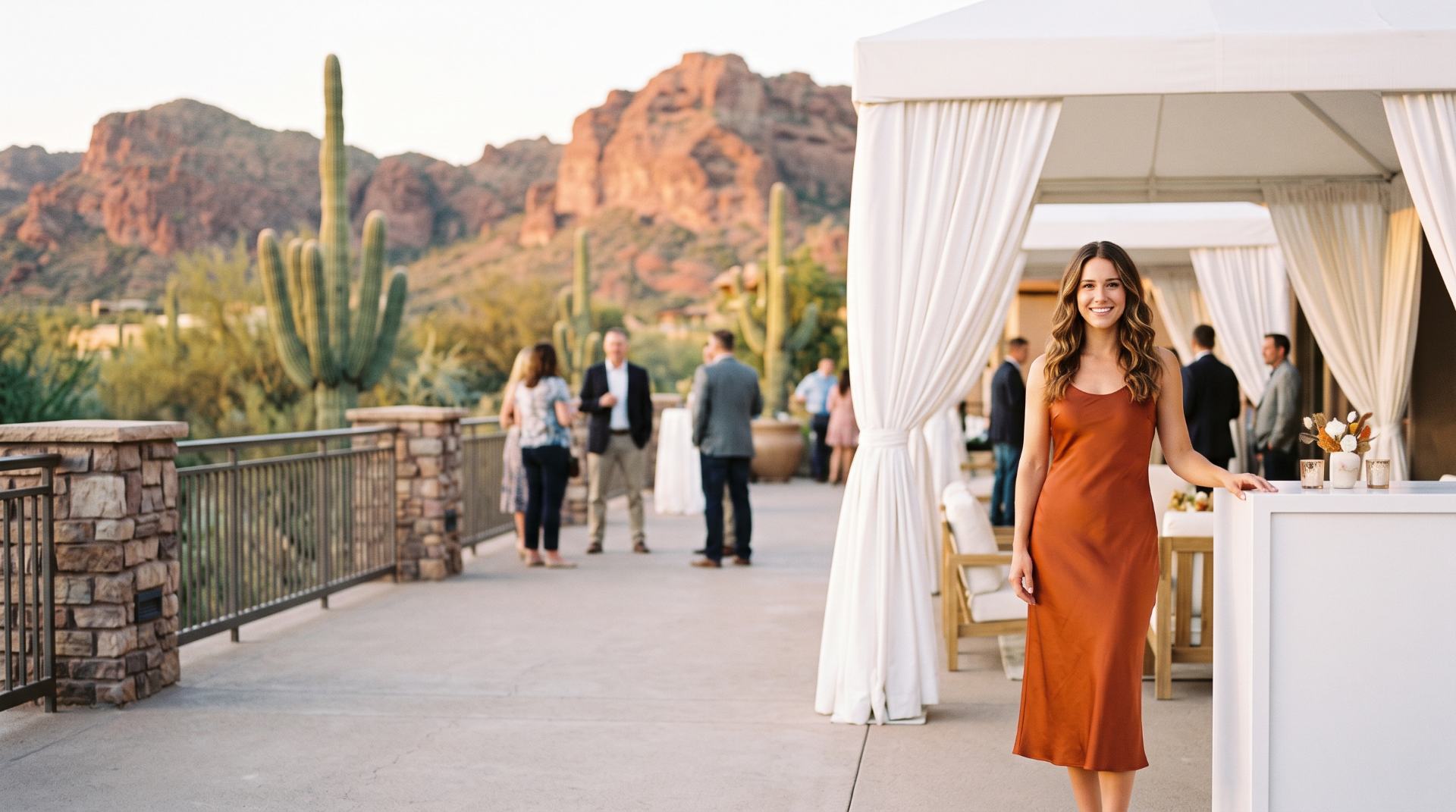 Brand ambassador in a burnt-orange satin dress at an outdoor resort conference terrace with saguaro cacti and red rock mountains, Phoenix
