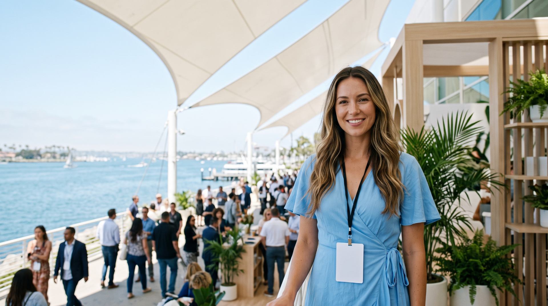 Brand ambassador in a sky-blue wrap dress on a sunny bayfront convention terrace with white sail canopies, San Diego