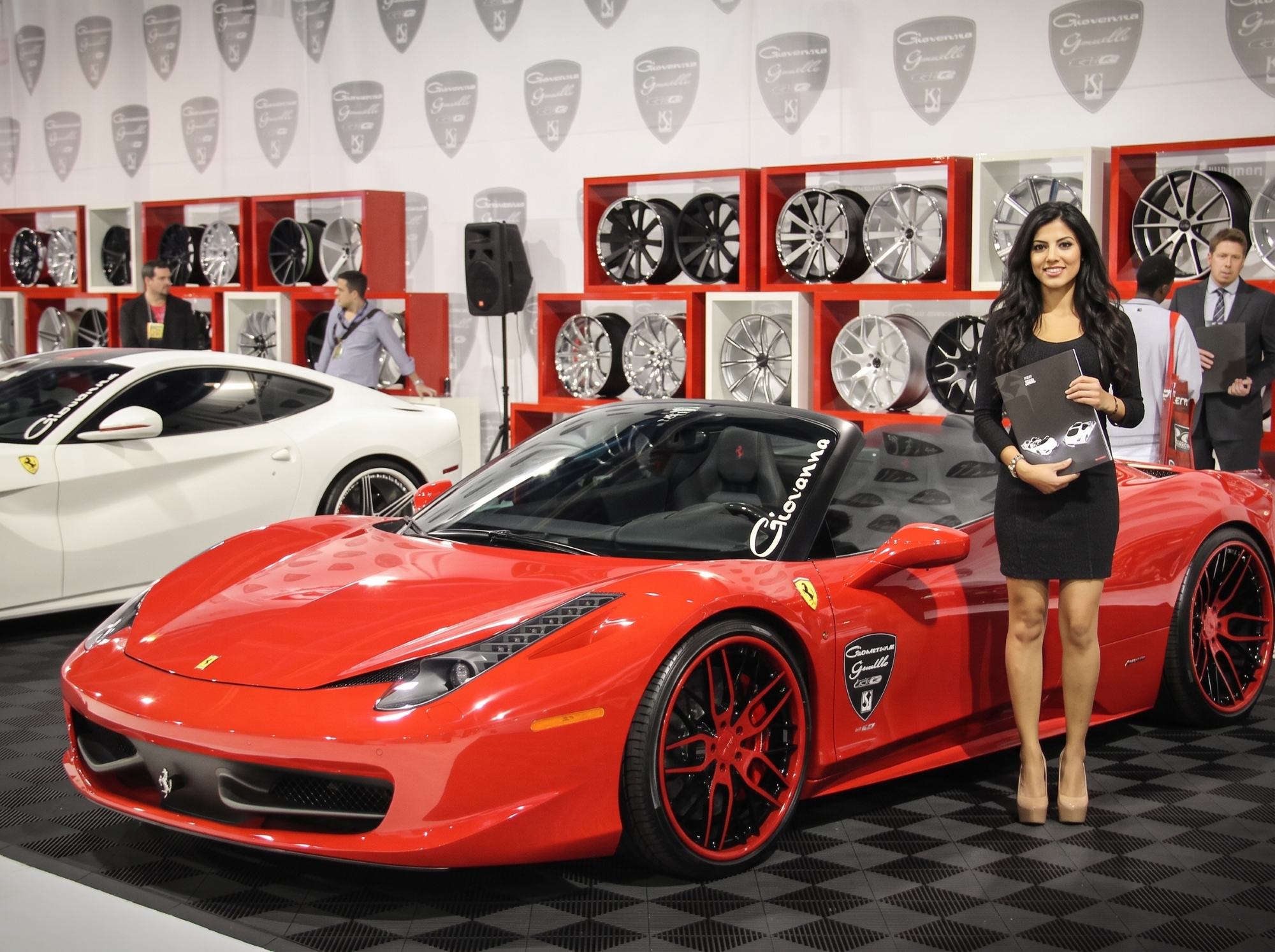 Trade show model beside a red sports car at a Las Vegas auto aftermarket show